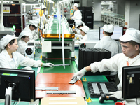 Workers rush to make computer and tablet battery orders at a workshop in Hai'an, China, on September 11, 2024. (