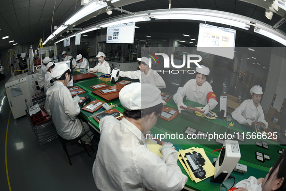 Workers rush to make computer and tablet battery orders at a workshop in Hai'an, China, on September 11, 2024. 