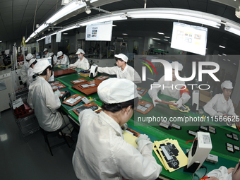 Workers rush to make computer and tablet battery orders at a workshop in Hai'an, China, on September 11, 2024. (