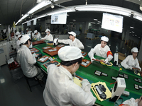 Workers rush to make computer and tablet battery orders at a workshop in Hai'an, China, on September 11, 2024. (