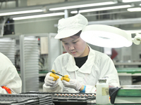 Workers rush to make computer and tablet battery orders at a workshop in Hai'an, China, on September 11, 2024. (