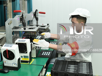 Workers rush to make computer and tablet battery orders at a workshop in Hai'an, China, on September 11, 2024. (