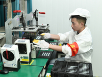 Workers rush to make computer and tablet battery orders at a workshop in Hai'an, China, on September 11, 2024. (