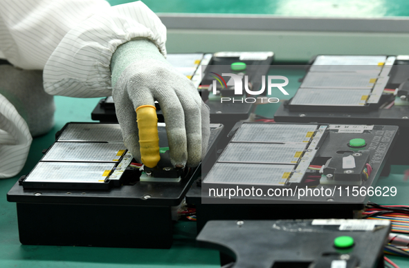 Workers rush to make computer and tablet battery orders at a workshop in Hai'an, China, on September 11, 2024. 