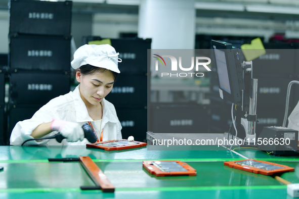 Workers rush to make computer and tablet battery orders at a workshop in Hai'an, China, on September 11, 2024. 