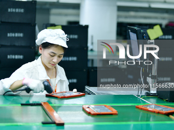 Workers rush to make computer and tablet battery orders at a workshop in Hai'an, China, on September 11, 2024. (