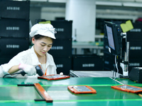 Workers rush to make computer and tablet battery orders at a workshop in Hai'an, China, on September 11, 2024. (