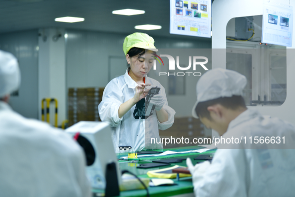 Workers rush to make computer and tablet battery orders at a workshop in Hai'an, China, on September 11, 2024. 