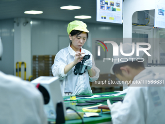 Workers rush to make computer and tablet battery orders at a workshop in Hai'an, China, on September 11, 2024. (