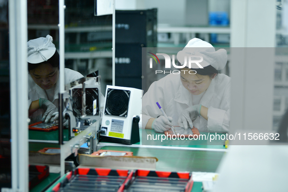 Workers rush to make computer and tablet battery orders at a workshop in Hai'an, China, on September 11, 2024. 