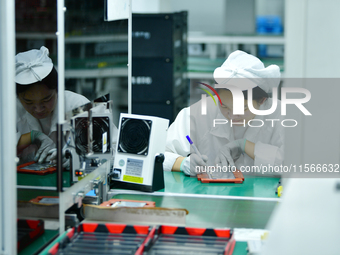 Workers rush to make computer and tablet battery orders at a workshop in Hai'an, China, on September 11, 2024. (