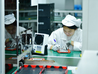 Workers rush to make computer and tablet battery orders at a workshop in Hai'an, China, on September 11, 2024. (