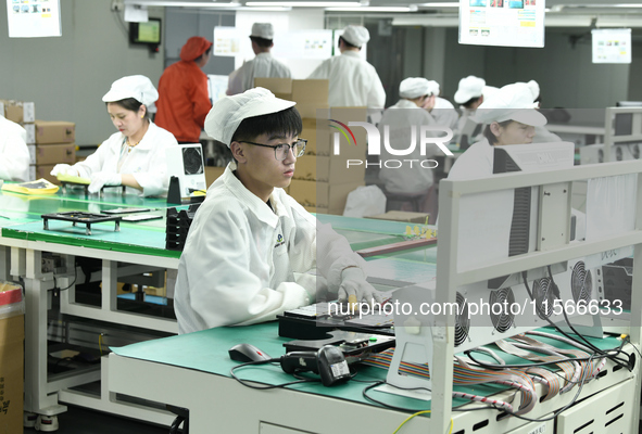 Workers rush to make computer and tablet battery orders at a workshop in Hai'an, China, on September 11, 2024. 