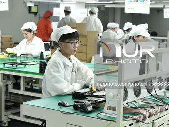 Workers rush to make computer and tablet battery orders at a workshop in Hai'an, China, on September 11, 2024. (