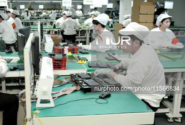 Workers rush to make computer and tablet battery orders at a workshop in Hai'an, China, on September 11, 2024. 