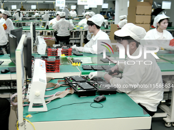 Workers rush to make computer and tablet battery orders at a workshop in Hai'an, China, on September 11, 2024. (