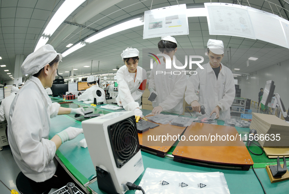 Workers rush to make computer and tablet battery orders at a workshop in Hai'an, China, on September 11, 2024. 