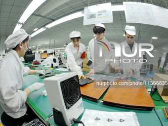 Workers rush to make computer and tablet battery orders at a workshop in Hai'an, China, on September 11, 2024. (