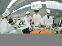 Workers rush to make computer and tablet battery orders at a workshop in Hai'an, China, on September 11, 2024. (