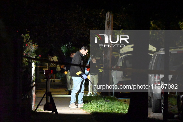 Crime scene investigators collect evidence at the scene where a man is killed by a shot to the head in Queens, New York, on September 11, 20...