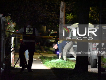 Crime scene investigators collect evidence at the scene where a man is killed by a shot to the head in Queens, New York, on September 11, 20...