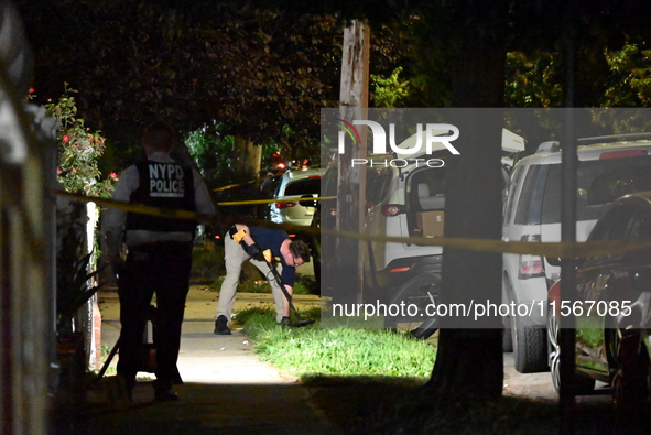 Crime scene investigators collect evidence at the scene where a man is killed by a shot to the head in Queens, New York, on September 11, 20...