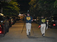 Crime scene investigators collect evidence at the scene where a man is killed by a shot to the head in Queens, New York, on September 11, 20...