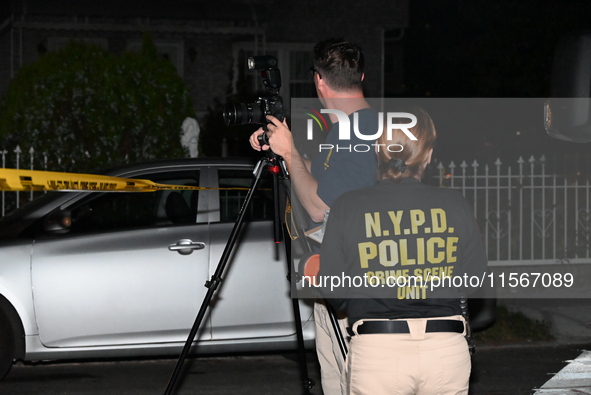 Crime scene investigators collect evidence at the scene where a man is killed by a shot to the head in Queens, New York, on September 11, 20...