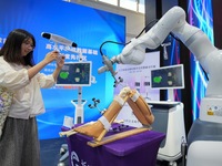 A viewer takes a photo of an artificial intelligence complete orthopedic digital solution at the 2024 China Beijing International Fair for T...