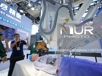 An exhibitor introduces a surgical robot to a visitor at the 2024 China Beijing International Fair for Trade in Services (CIFTIS) in Beijing...