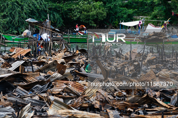 People work on boats near the rubble of damaged houses following a fire that engulfs at least 800 houses in Bacoor, Cavite, the Philippines,...