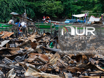 People work on boats near the rubble of damaged houses following a fire that engulfs at least 800 houses in Bacoor, Cavite, the Philippines,...