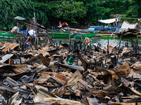 People work on boats near the rubble of damaged houses following a fire that engulfs at least 800 houses in Bacoor, Cavite, the Philippines,...