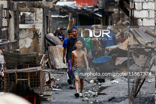 People walk along the narrow streets of damaged houses following a huge fire that engulfs at least 800 houses in Bacoor, Cavite, the Philipp...