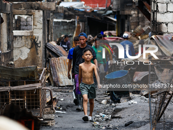 People walk along the narrow streets of damaged houses following a huge fire that engulfs at least 800 houses in Bacoor, Cavite, the Philipp...