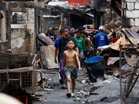 People walk along the narrow streets of damaged houses following a huge fire that engulfs at least 800 houses in Bacoor, Cavite, the Philipp...