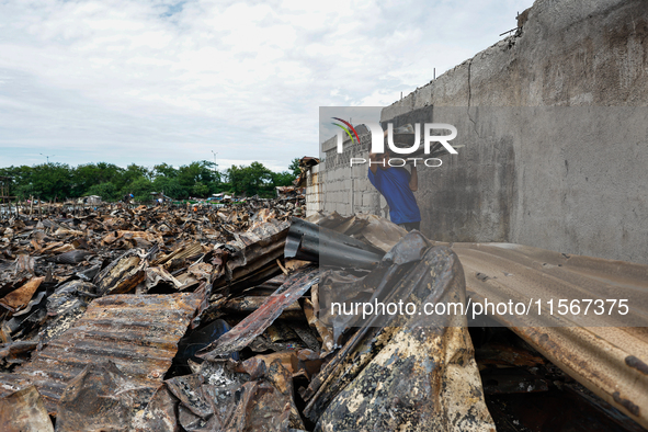 In Bacoor, Cavite, the Philippines, on September 12, 2024, a man carries burnt iron sheets from the rubble of damaged houses following a hug...