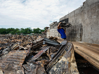 In Bacoor, Cavite, the Philippines, on September 12, 2024, a man carries burnt iron sheets from the rubble of damaged houses following a hug...