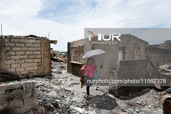 In Bacoor, Cavite, the Philippines, on September 12, 2024, resident Ms. Sharon holds an umbrella and surveys the rubble of her damaged house...