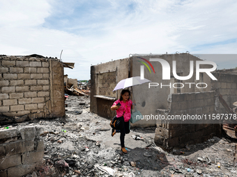 In Bacoor, Cavite, the Philippines, on September 12, 2024, resident Ms. Sharon holds an umbrella and surveys the rubble of her damaged house...