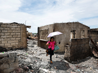 In Bacoor, Cavite, the Philippines, on September 12, 2024, resident Ms. Sharon holds an umbrella and surveys the rubble of her damaged house...