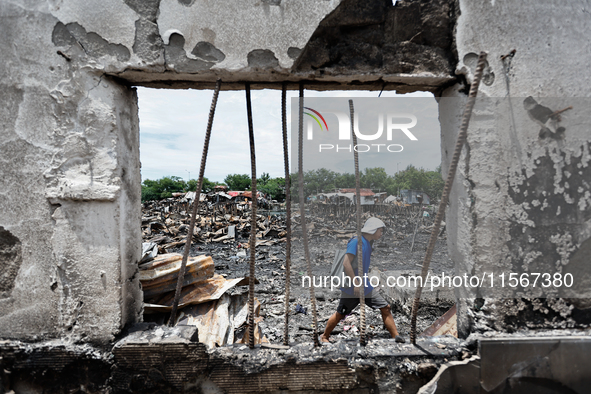 A man walks atop the rubble of damaged houses following a huge fire that engulfs at least 800 houses in Bacoor, Cavite, the Philippines, on...