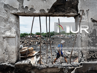 A man walks atop the rubble of damaged houses following a huge fire that engulfs at least 800 houses in Bacoor, Cavite, the Philippines, on...