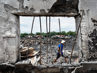 A man walks atop the rubble of damaged houses following a huge fire that engulfs at least 800 houses in Bacoor, Cavite, the Philippines, on...