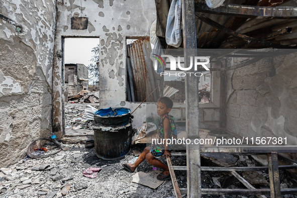 A boy sits on a burnt metal bunk bed inside a damaged house following a huge fire that engulfs at least 800 houses in Bacoor, Cavite, the Ph...