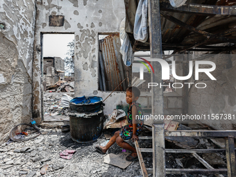 A boy sits on a burnt metal bunk bed inside a damaged house following a huge fire that engulfs at least 800 houses in Bacoor, Cavite, the Ph...