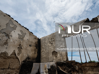 A plane takes off, seen through the collapsed rooftop of damaged houses, following a fire that engulfs at least 800 houses in Bacoor, Cavite...