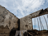 A plane takes off, seen through the collapsed rooftop of damaged houses, following a fire that engulfs at least 800 houses in Bacoor, Cavite...