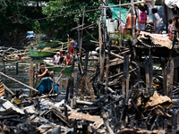 People on boats paddle near the rubble of damaged houses following a huge fire that engulfs at least 800 houses in Bacoor, Cavite, the Phili...