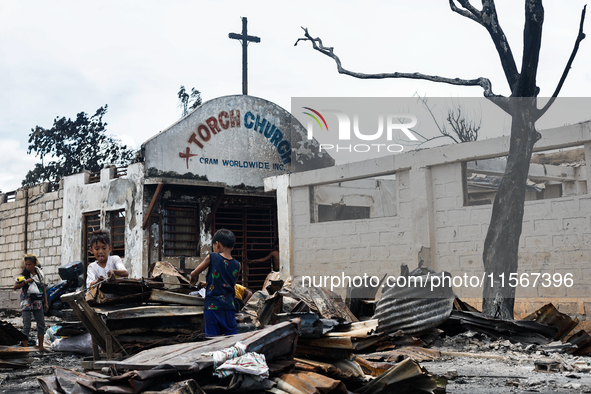 Children help remove the debris of damaged houses following a huge fire that engulfs at least 800 houses in Bacoor, Cavite, the Philippines,...